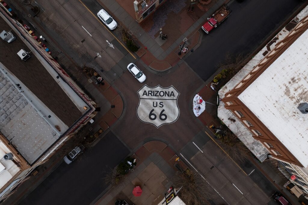 an aerial shot of a four-way intersection with a Route 66 icon painted onto the street