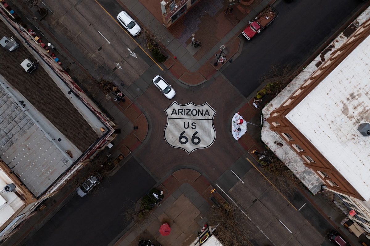 an aerial shot of a four-way intersection with a Route 66 icon painted onto the street