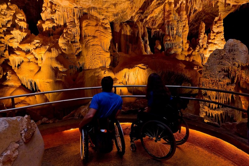 two people in wheelchairs sitting on a platform inside of a cavern
