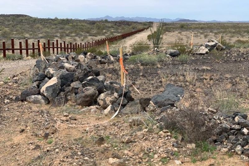 desert landscape with a fence and wooden posts connected by tape