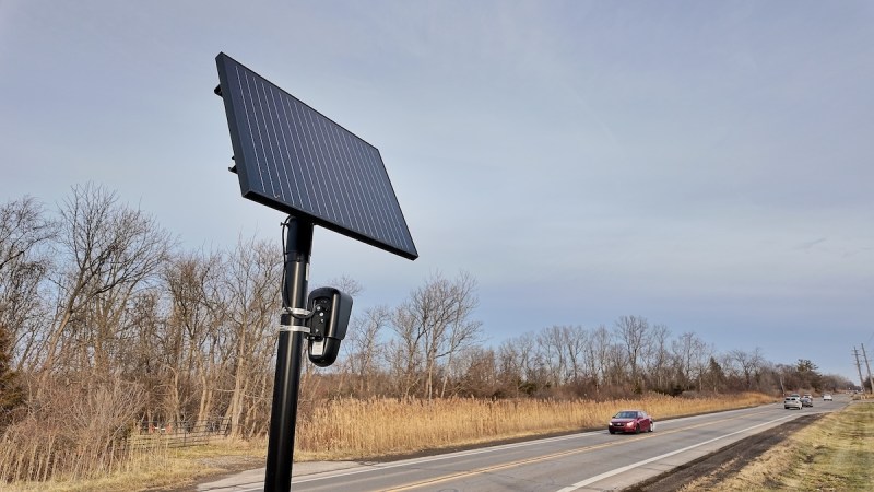 a black panel on top of a pole sitting along a road