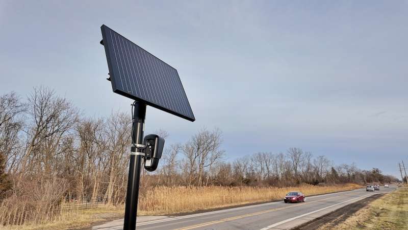 a black panel on top of a pole sitting along a road