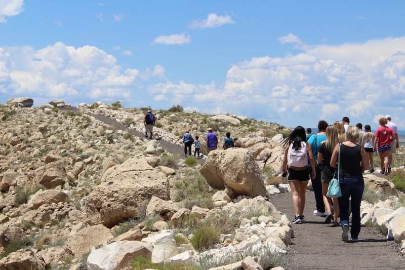 people walking a path up a hill in a desert landscape