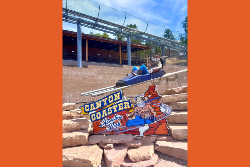 a sign that says Canyon Coaster Adventure Park with a model of the coaster seat