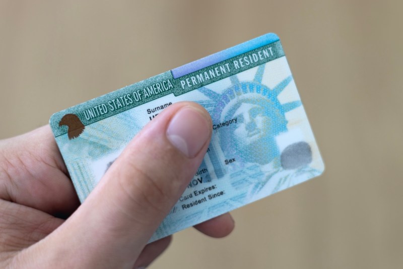 hand holding a card that says United States of American permanent resident