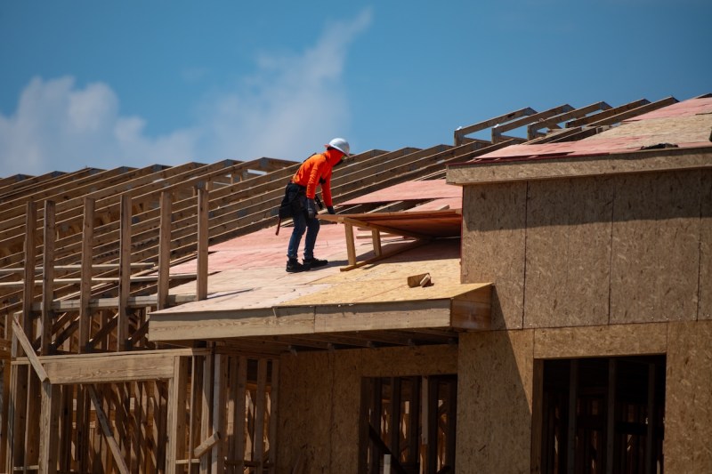 construction worker on a roof being built from wood planks