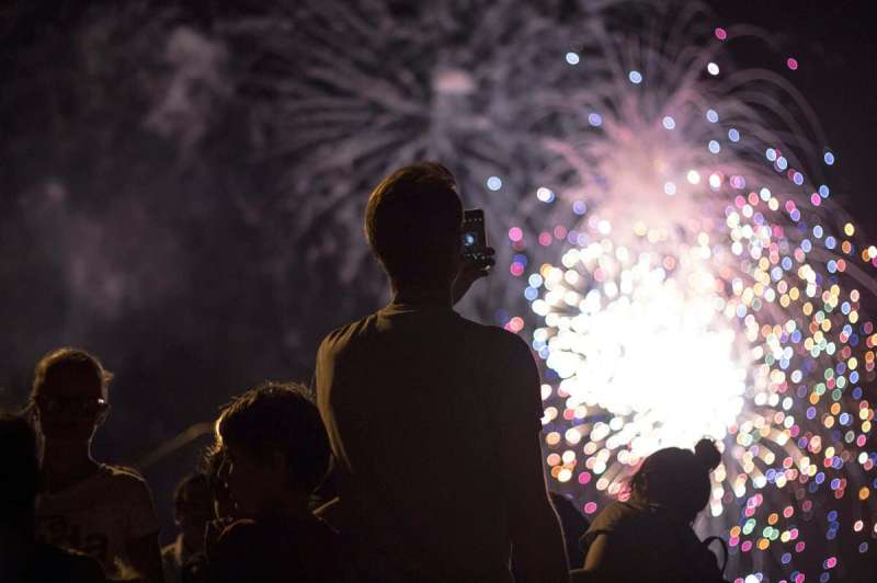 A man records a firework display at one of Arizona's 4th of July events