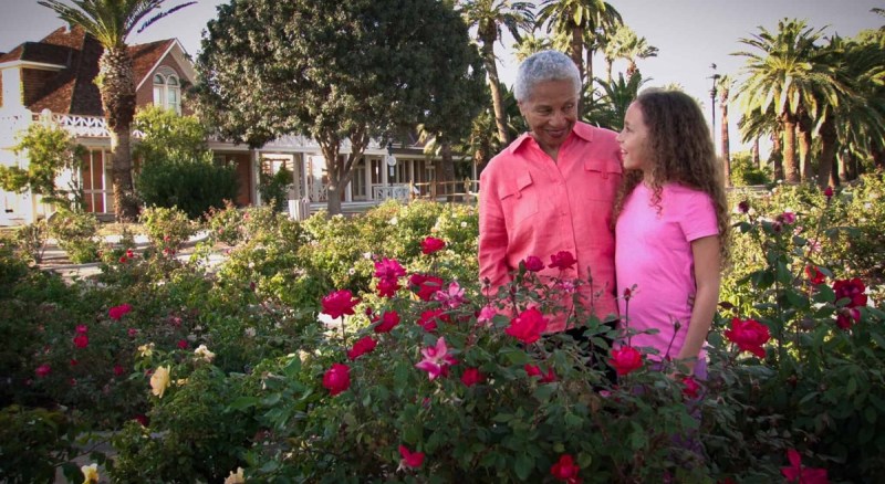 A child stands with an older woman in a beautiful garden