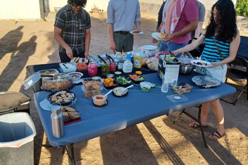 people standing around a table putting dishes from the table on plates