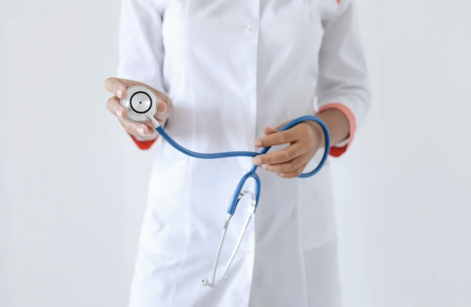 person wearing white coat holding stethoscope