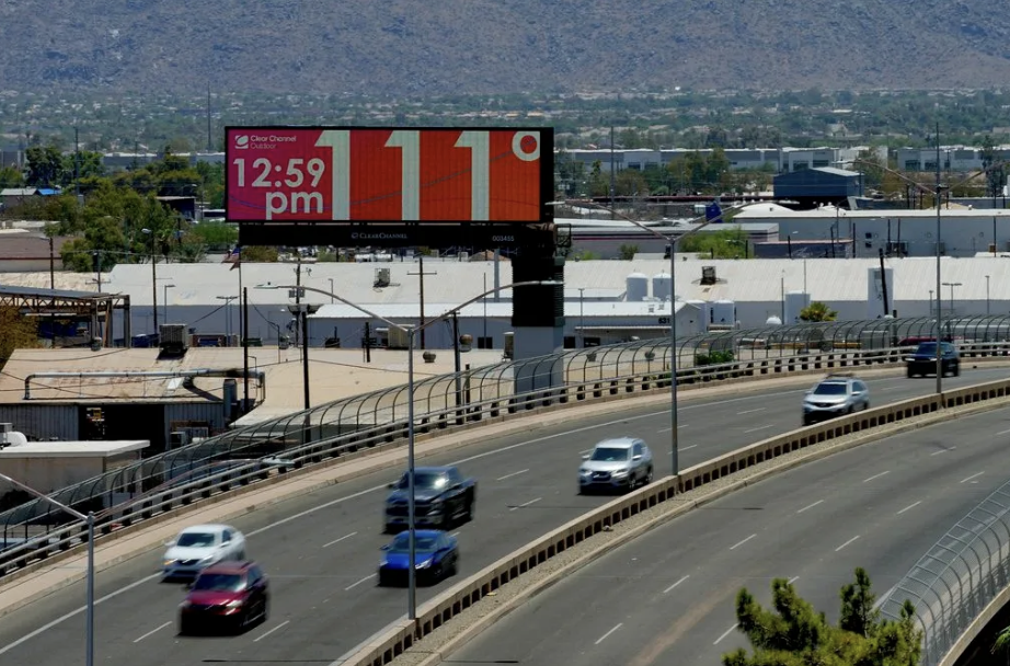 cars driving on a freeway next to a billboard that says 12:59 p.m., 111 degrees