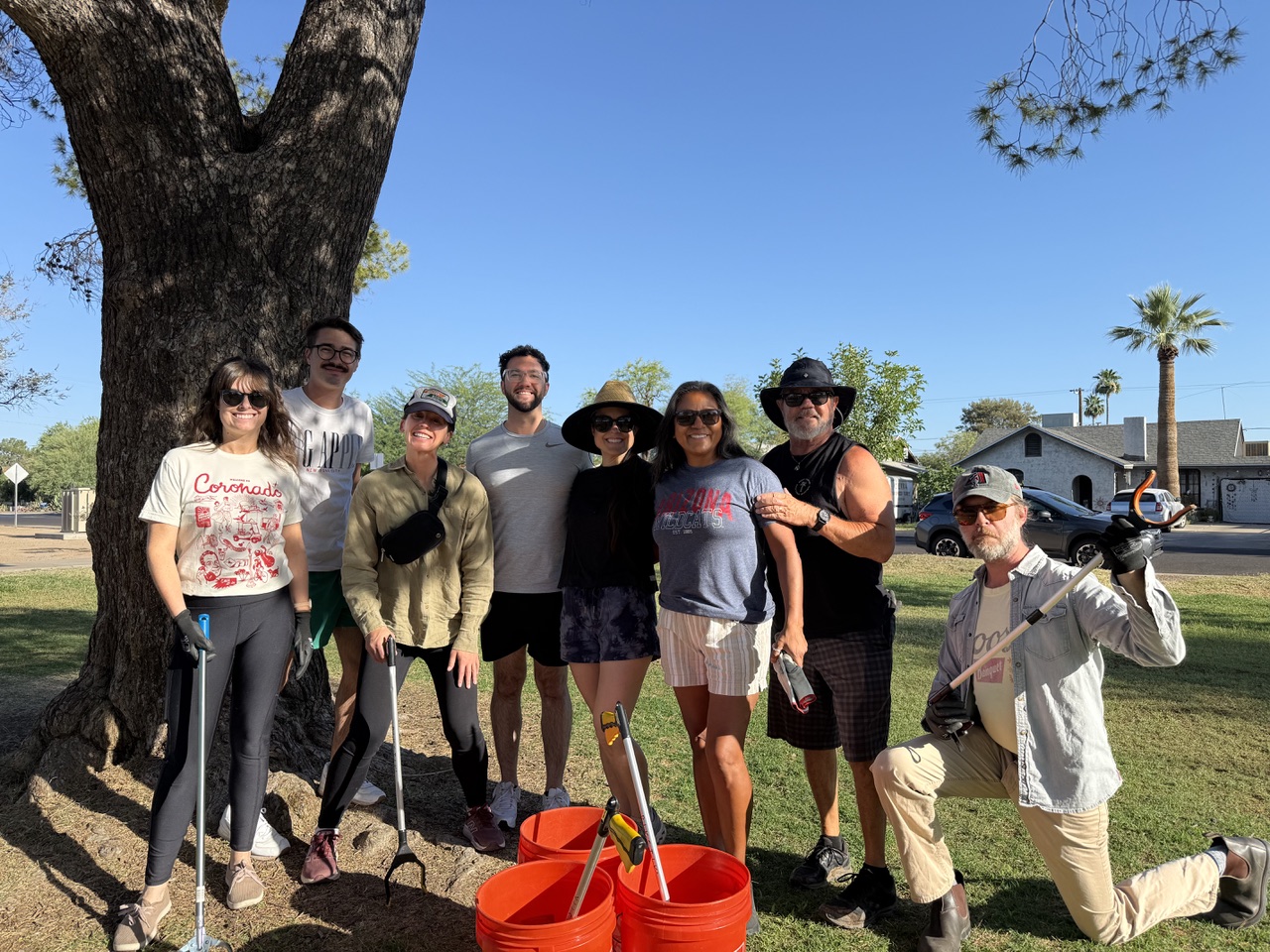 a group of people posing outdoors holding grabber sticks