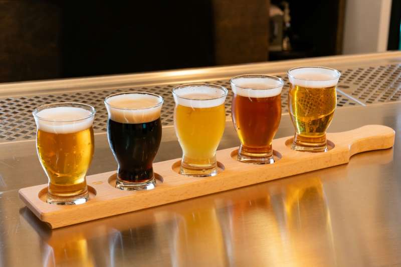 a flight of different kinds of beer sitting on a counter