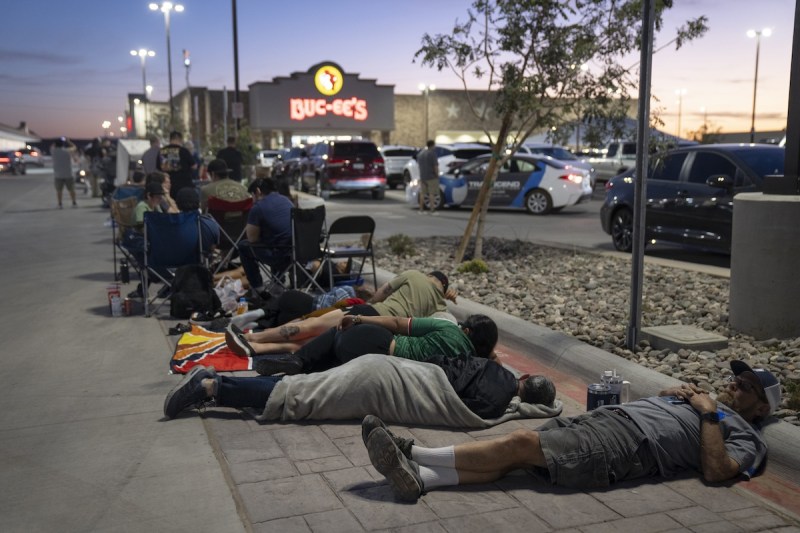 people lying on ground and sitting on chairs outside of a Buc-ee's
