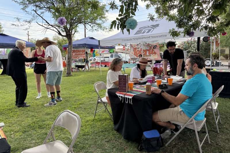 people standing and sitting at tables in a street fair setting
