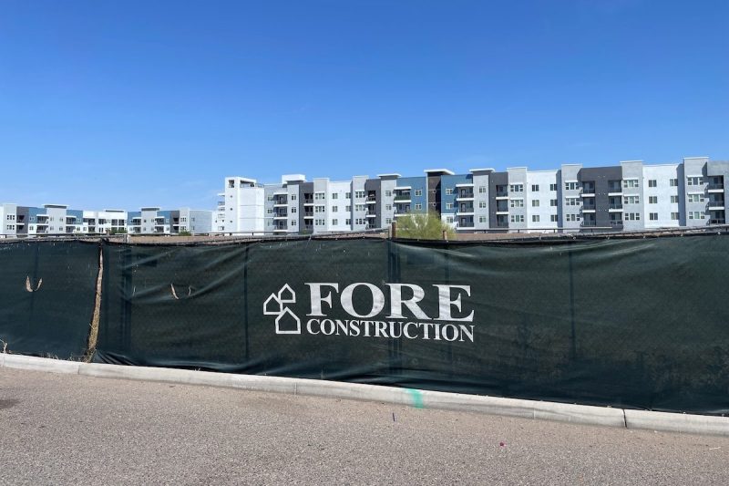 apartment buildings surrounded by a fence with a sign that says FORE Construction