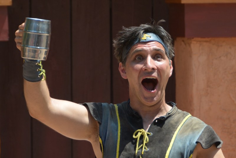 a man in renaissance costume holding up a mug