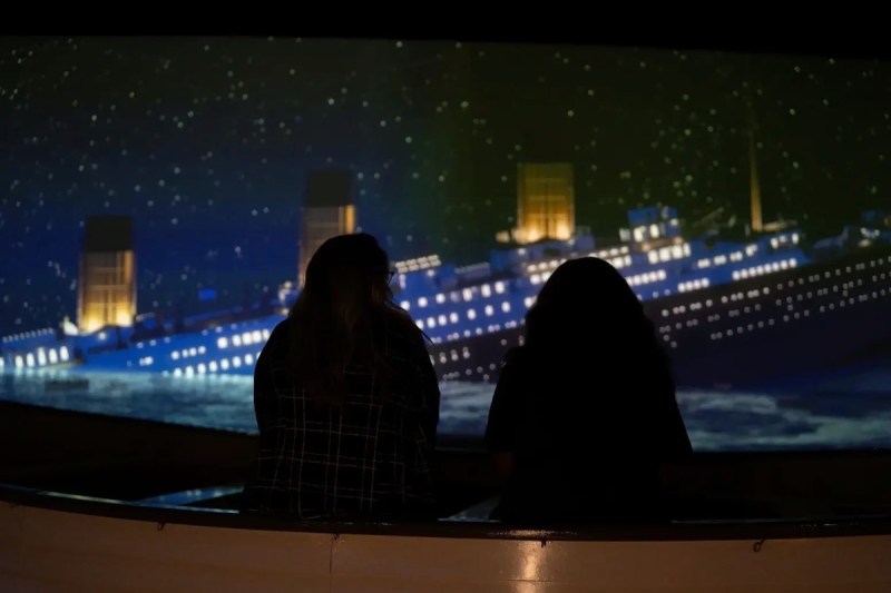 silhouette of two people viewing an image of the Titanic sinking