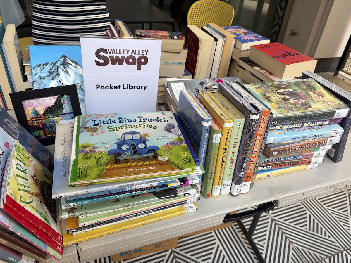 a table full of books with a sign that says Valley Alley Swap pocket library