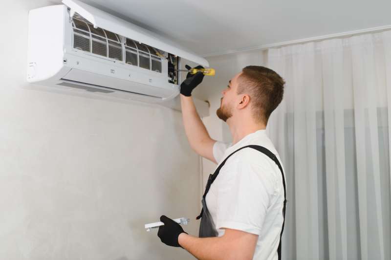 man using screwdriver on wall AC unit